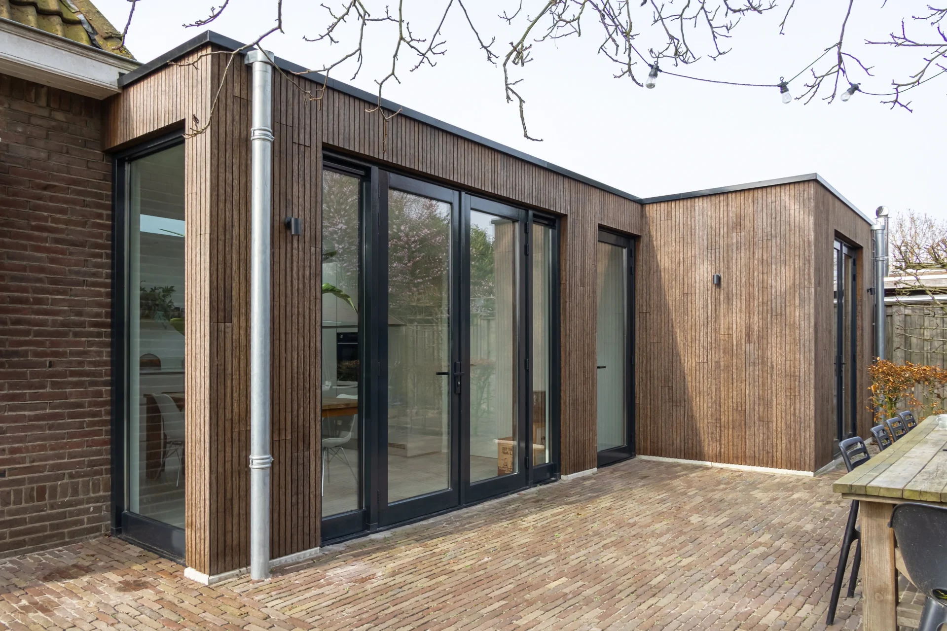 Moderne woninguitbouw met houten gevelbekleding en zwarte kozijnen